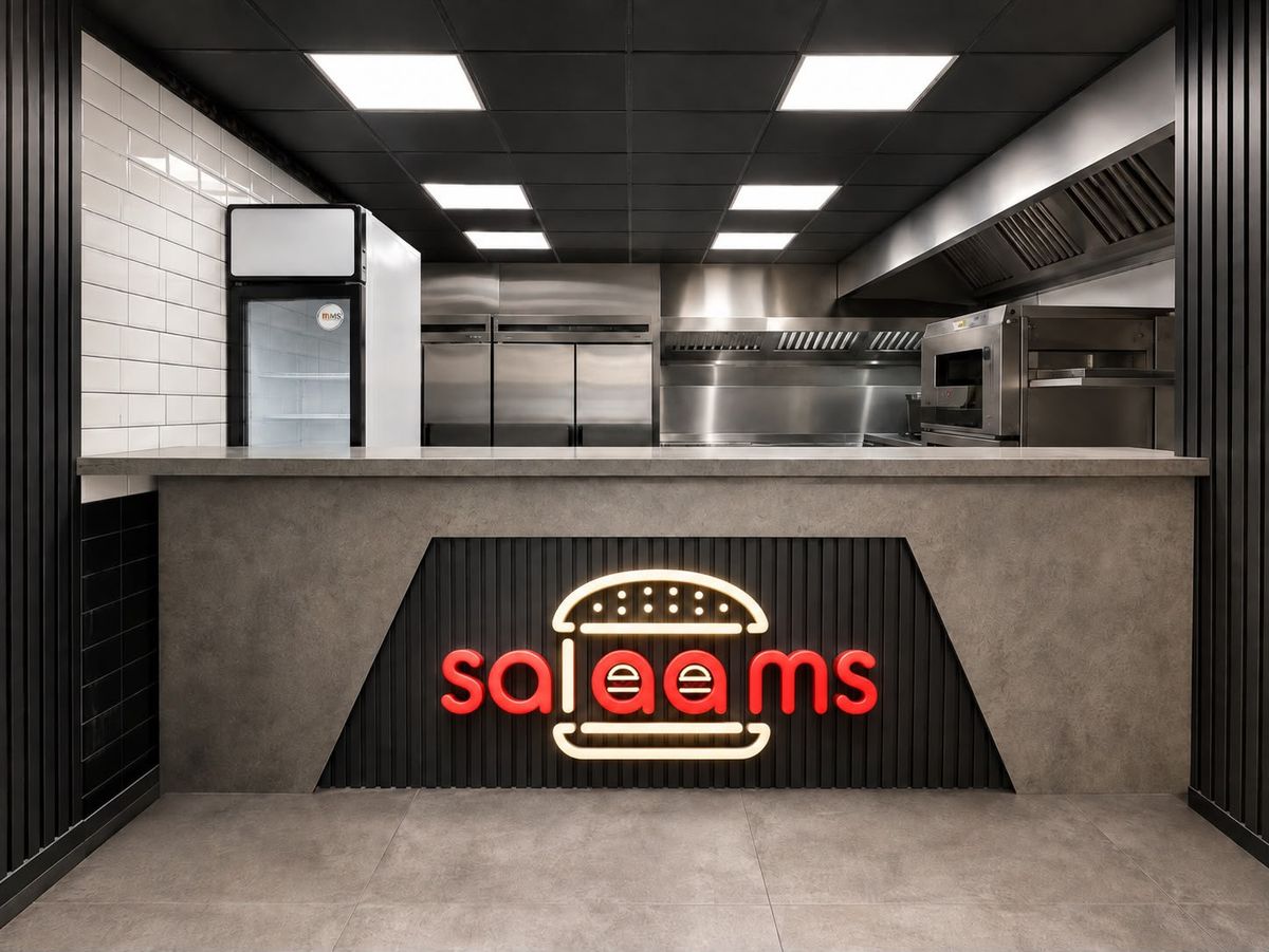 The Salaams counter with the neon burger logo sign and open kitchen